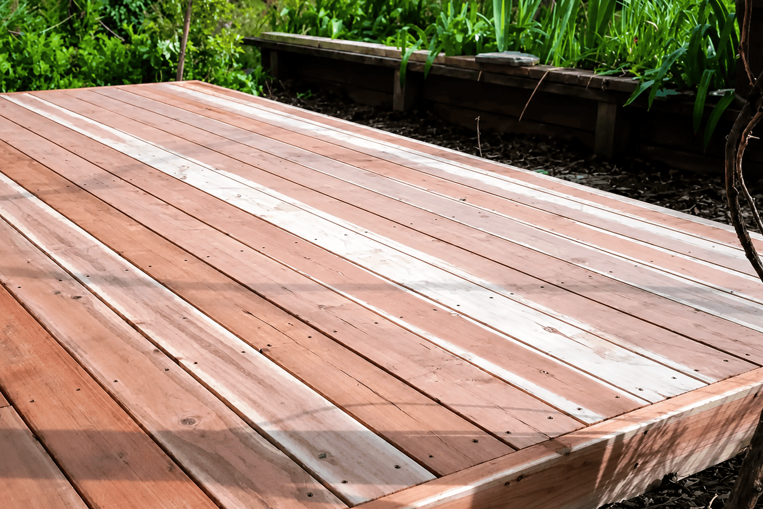 Sacramento backyard deck comparing composite and redwood decking materials in sunlight