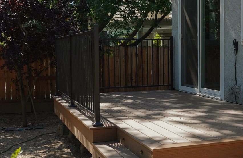 Redwood Decks Redwood deck with natural wood grain attached to a backyard patio