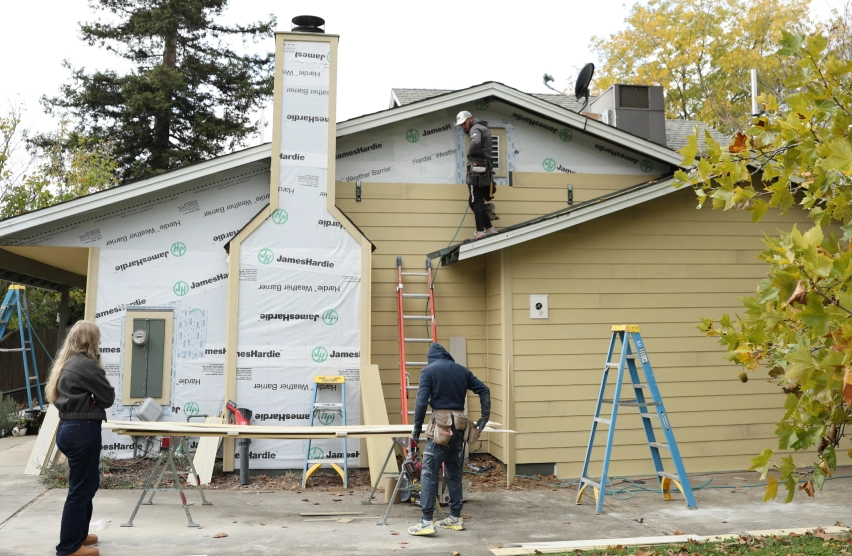 Residential home exterior with siding removed to reveal the layer beneath the panels