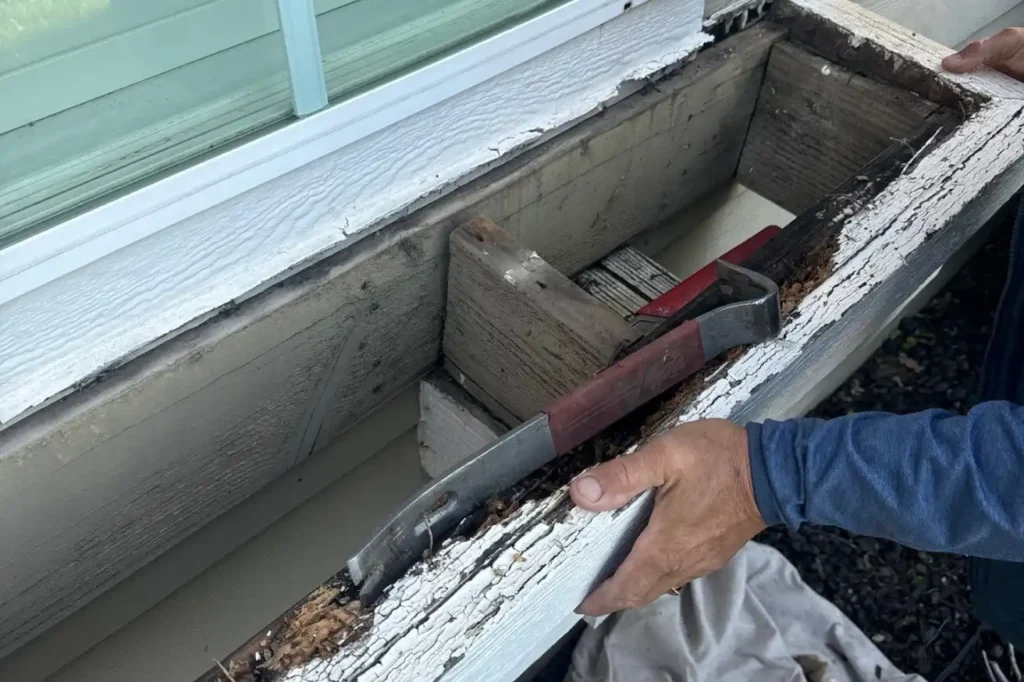Isolated siding damage that only needs repair Contractor using a pry bar to remove severely rotted and peeling wood from an exterior window or trim assembly