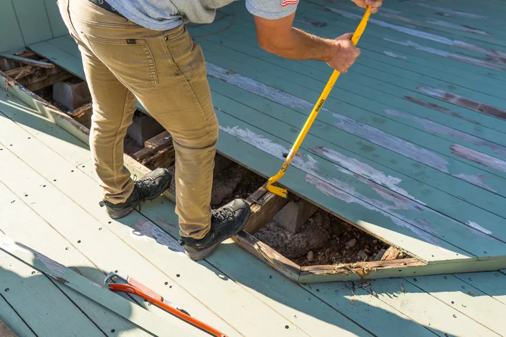 Resale value gains from new siding Contractor examining rim joist connection behind removed deck boards