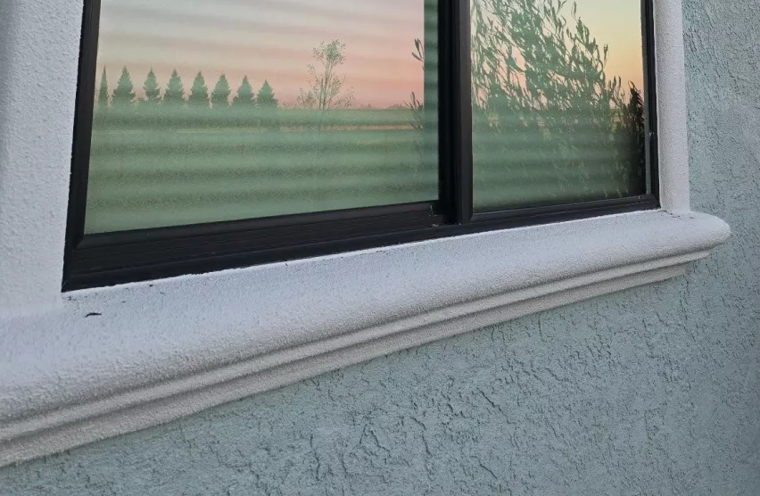 New dark-frame window with a clean stucco sill after window replacement in Rancho Cordova