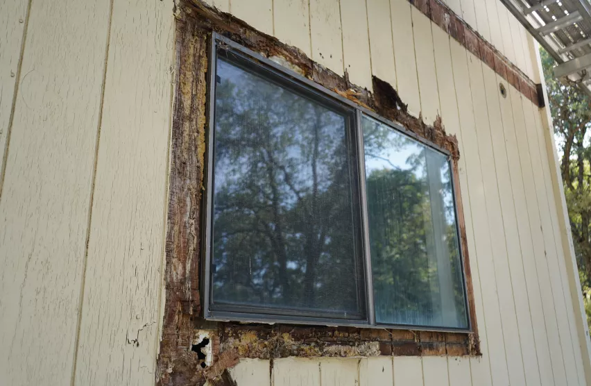 Weathered window opening with rotted trim and damaged siding before replacement
