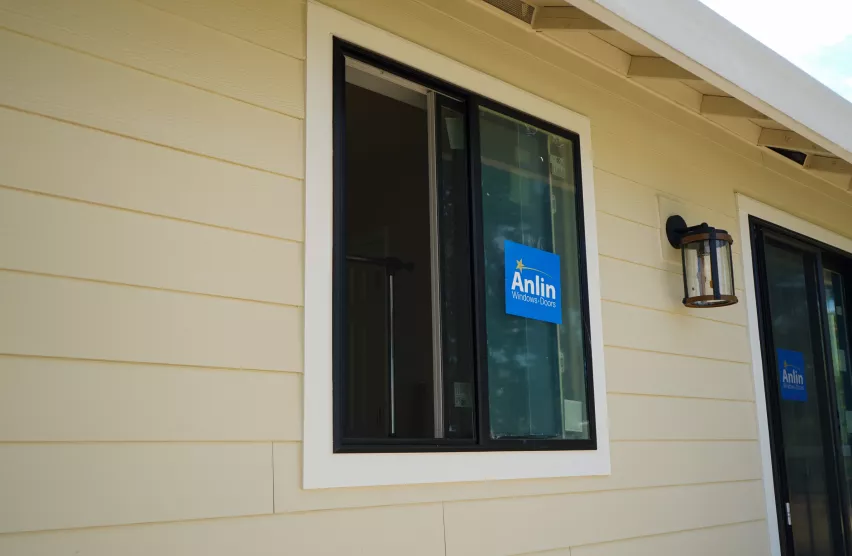 Black-frame Anlin replacement window with new white trim on an Elk Grove home