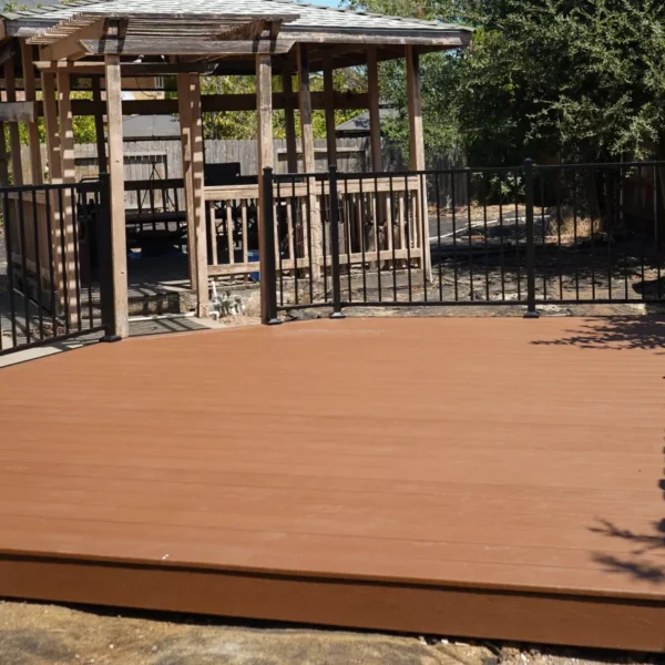 Newly built Trex composite deck with black metal railing in a compact Sacramento backyard.