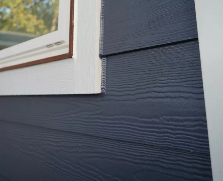 Blue James Hardie siding with clean trim details around a window.