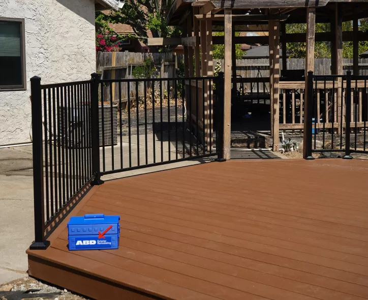 Finished Trex composite deck surface with black metal railing.