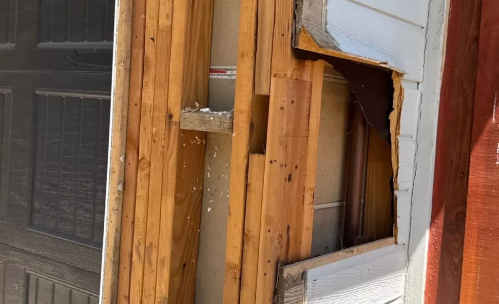 Hands filling a damaged siding board with epoxy filler